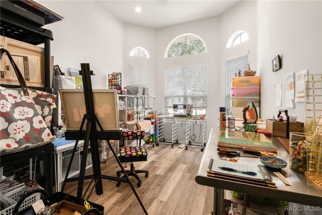 office with light hardwood / wood-style floors and a high ceiling