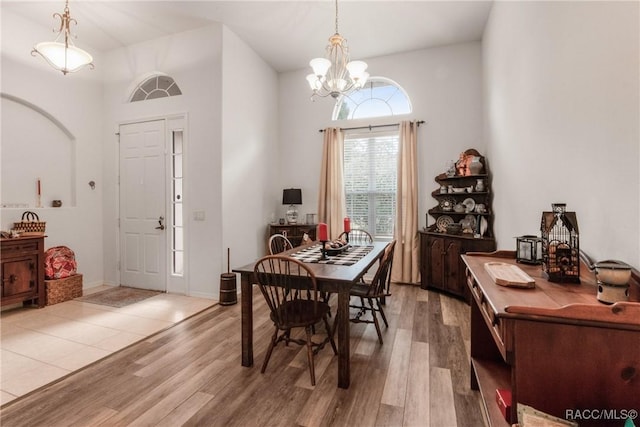 dining area with hardwood / wood-style floors, a chandelier, and a high ceiling