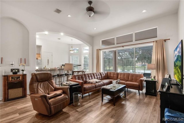 living room featuring ceiling fan with notable chandelier and hardwood / wood-style flooring