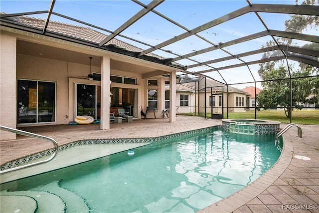 view of pool featuring glass enclosure, ceiling fan, a patio, and an in ground hot tub