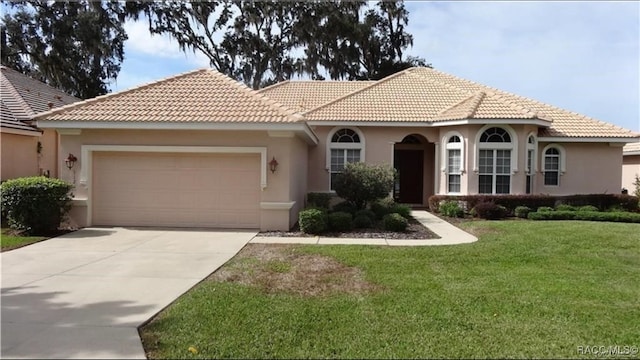 mediterranean / spanish-style house featuring a front yard and a garage