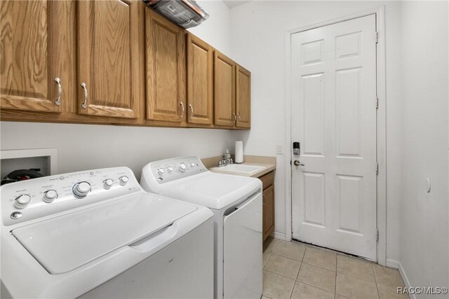 laundry room with cabinets, light tile patterned floors, washer and clothes dryer, and sink