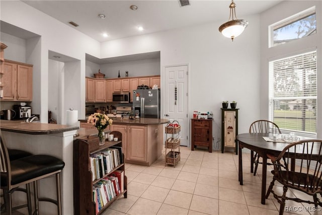 kitchen featuring light brown cabinets, a center island, a healthy amount of sunlight, and appliances with stainless steel finishes