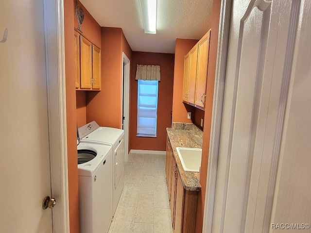 laundry area with sink, cabinets, independent washer and dryer, a textured ceiling, and light tile patterned floors