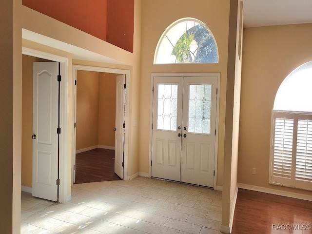 entrance foyer with french doors, a healthy amount of sunlight, and light hardwood / wood-style floors