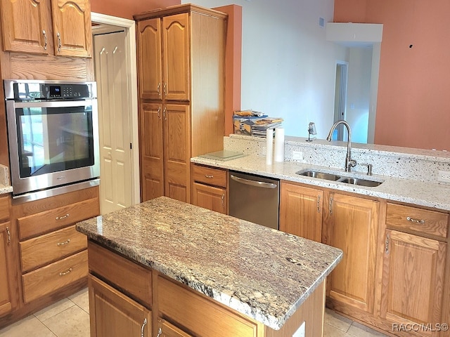 kitchen featuring light stone countertops, light tile patterned floors, stainless steel appliances, and sink