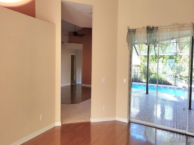 empty room featuring a high ceiling, hardwood / wood-style flooring, and ceiling fan