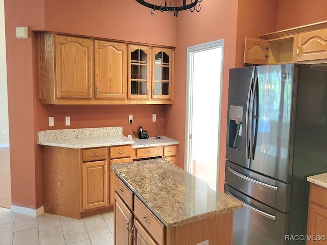 kitchen featuring light stone counters, light tile patterned floors, and stainless steel refrigerator with ice dispenser