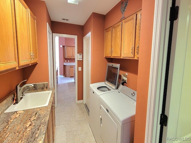 laundry room with washer and clothes dryer, sink, light tile patterned floors, and cabinets