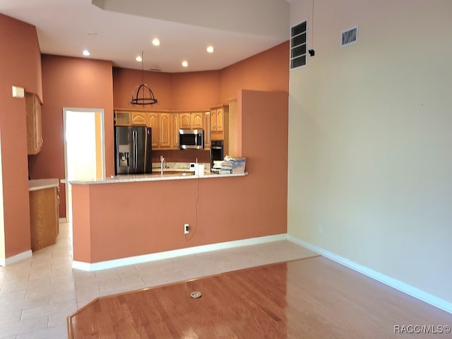 kitchen featuring black appliances, sink, light tile patterned floors, decorative light fixtures, and kitchen peninsula