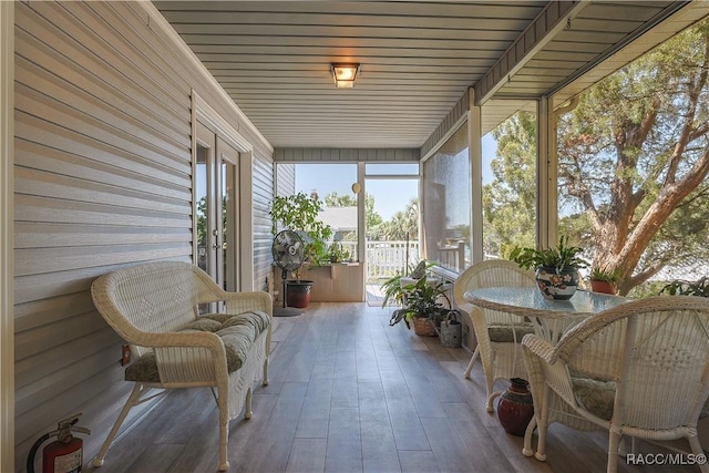 sunroom with wooden walls, french doors, and wood finished floors