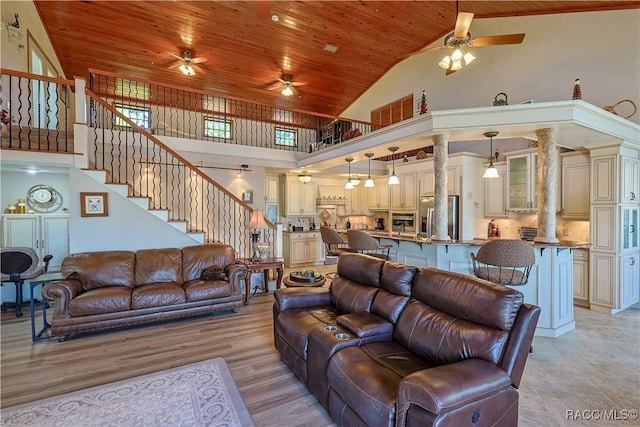 living room featuring high vaulted ceiling, a ceiling fan, wooden ceiling, and stairway