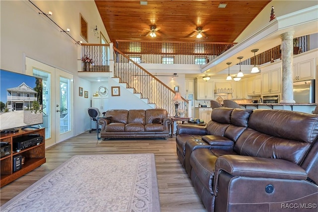 living area with a ceiling fan, wooden ceiling, a towering ceiling, and stairs