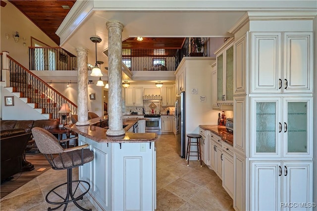 kitchen featuring appliances with stainless steel finishes, a breakfast bar, ornate columns, and a peninsula