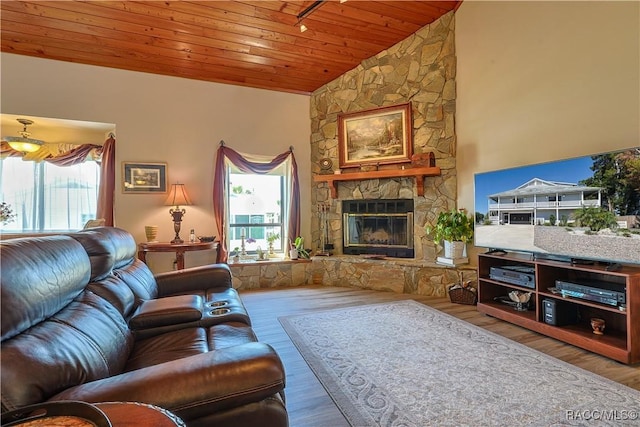 living area with a stone fireplace, wood ceiling, vaulted ceiling, and wood finished floors
