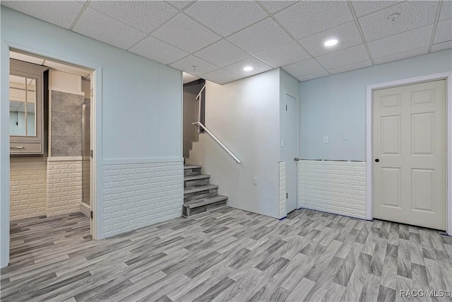 basement with light wood-style flooring, stairs, a wainscoted wall, and recessed lighting