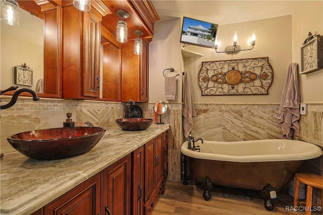 full bathroom featuring a freestanding tub, wood finished floors, a sink, tile walls, and double vanity