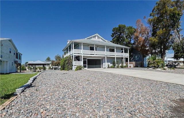 beach home featuring an attached garage, driveway, a front yard, and a balcony