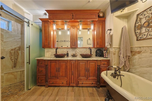 full bath with wood finished floors, a sink, and a soaking tub