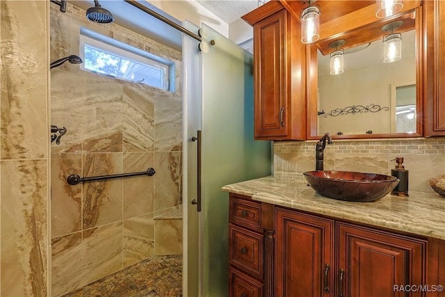 bathroom with a tile shower, vanity, and decorative backsplash