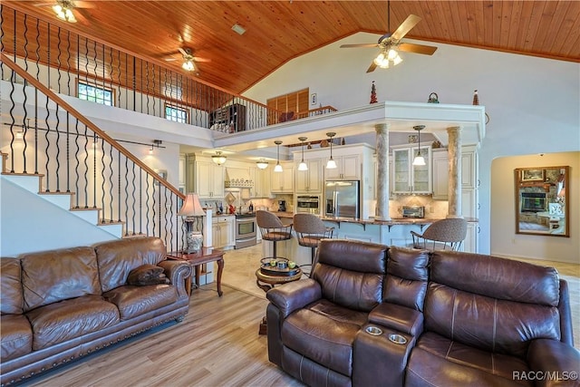 living room featuring high vaulted ceiling, a ceiling fan, wooden ceiling, and stairway