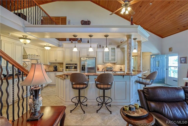 kitchen featuring stainless steel appliances, tasteful backsplash, high vaulted ceiling, and a kitchen breakfast bar