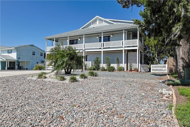 raised beach house with fence, driveway, and a gate