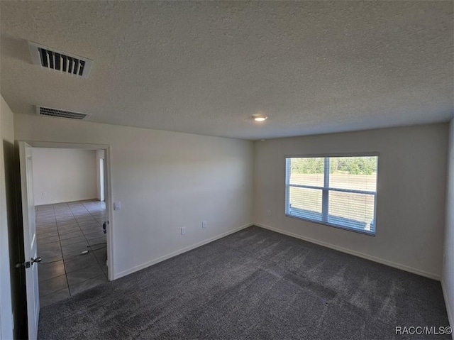 empty room with a textured ceiling and dark colored carpet