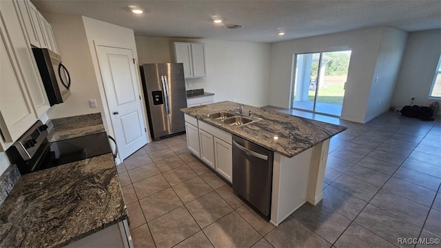 kitchen featuring tile patterned flooring, sink, white cabinetry, an island with sink, and stainless steel appliances