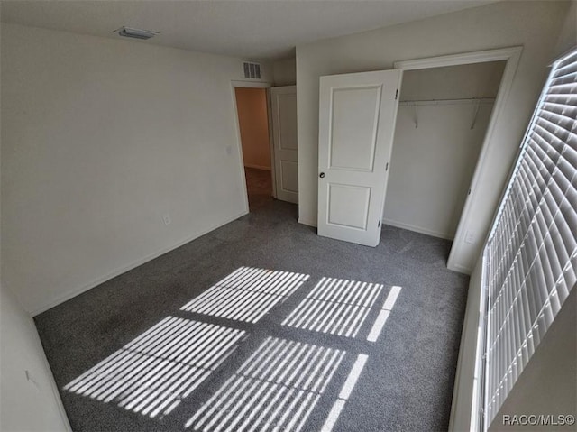 unfurnished bedroom featuring a closet and dark colored carpet