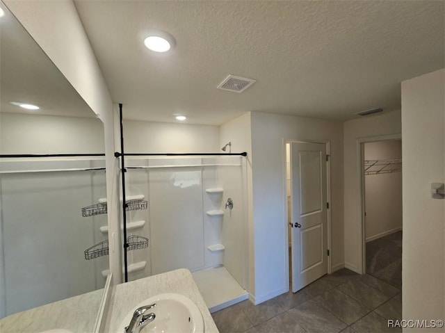 bathroom with vanity, tile patterned flooring, a textured ceiling, and walk in shower