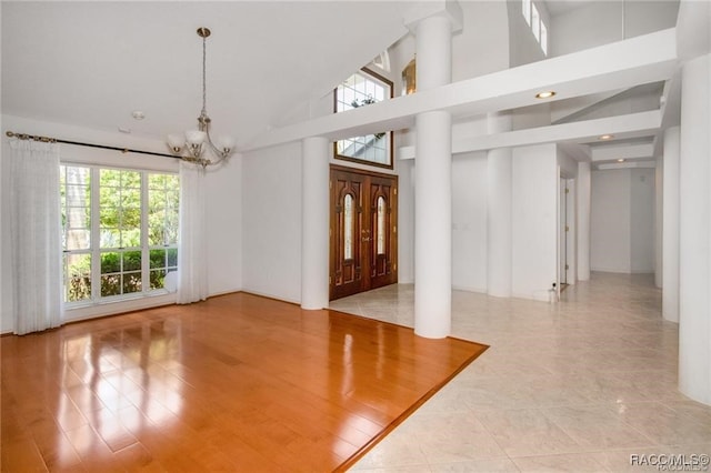 foyer entrance featuring a chandelier, high vaulted ceiling, and light hardwood / wood-style floors