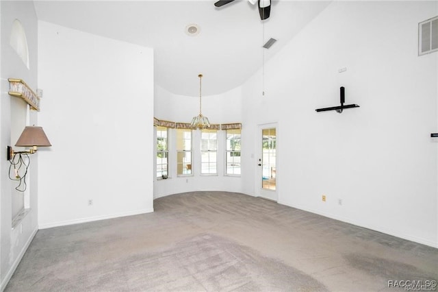 unfurnished living room featuring carpet, ceiling fan with notable chandelier, and high vaulted ceiling