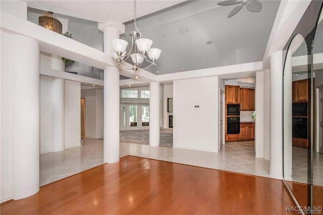 interior space with ceiling fan with notable chandelier and light wood-type flooring