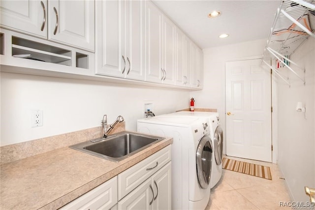 laundry room with washing machine and dryer, sink, light tile patterned flooring, and cabinets