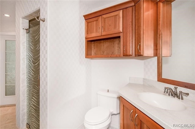 bathroom with toilet, vanity, and tiled shower