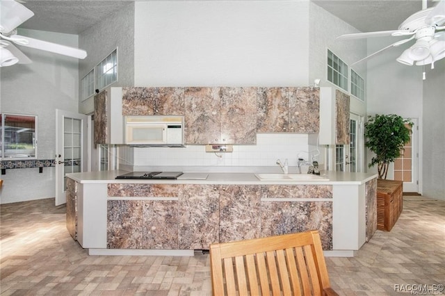 kitchen with kitchen peninsula, a high ceiling, a textured ceiling, and sink