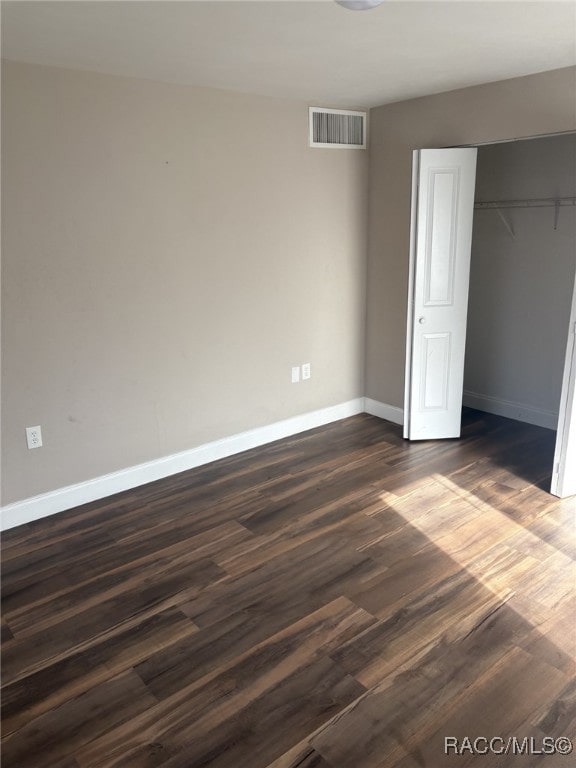 unfurnished bedroom with dark hardwood / wood-style floors and a closet