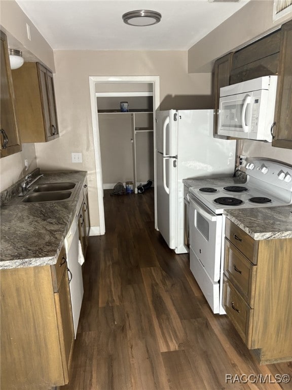 kitchen with dark hardwood / wood-style flooring, sink, white appliances, and dark stone countertops