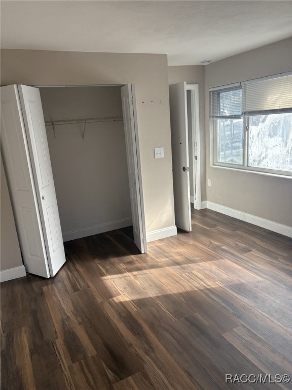 unfurnished bedroom featuring a closet and dark wood-type flooring