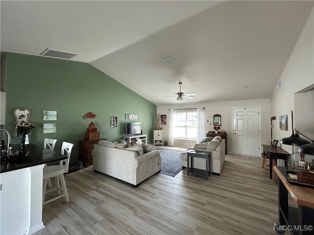 living area featuring ceiling fan, visible vents, vaulted ceiling, and wood finished floors