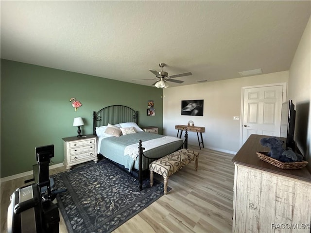 bedroom featuring visible vents, baseboards, ceiling fan, wood finished floors, and a textured ceiling