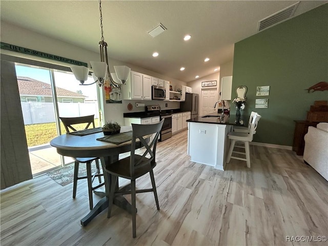 dining area with lofted ceiling, light wood finished floors, visible vents, and an inviting chandelier