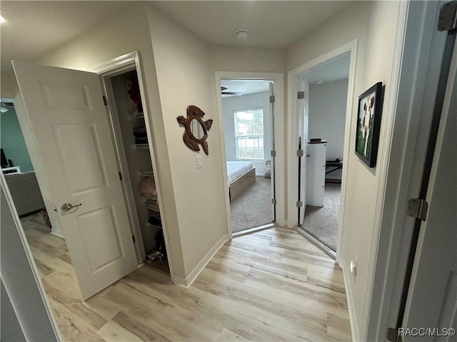 hall featuring light wood-style flooring and baseboards