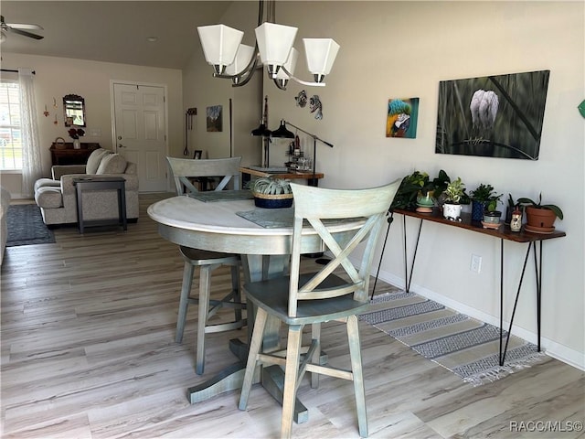 dining space featuring light wood-style floors, baseboards, and ceiling fan with notable chandelier