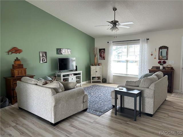 living area with lofted ceiling, ceiling fan, a textured ceiling, baseboards, and light wood finished floors