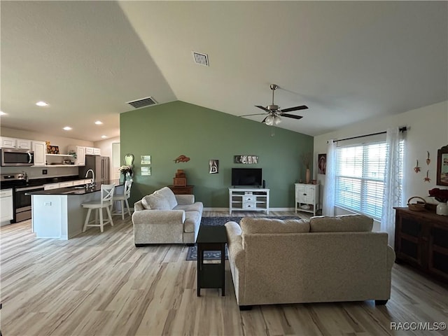 living area with light wood finished floors, visible vents, and vaulted ceiling