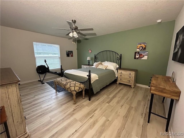 bedroom with a ceiling fan, light wood-type flooring, a textured ceiling, and baseboards