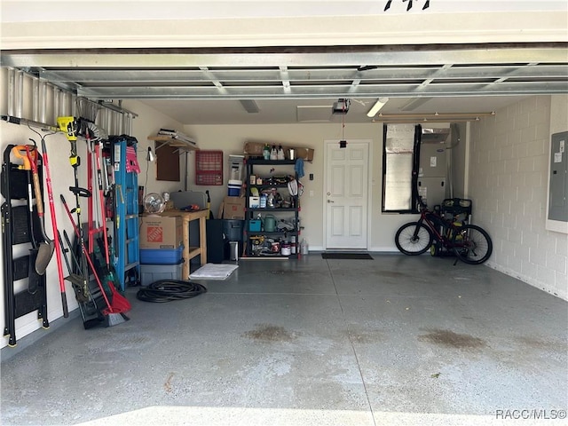 garage featuring concrete block wall, electric panel, and a garage door opener