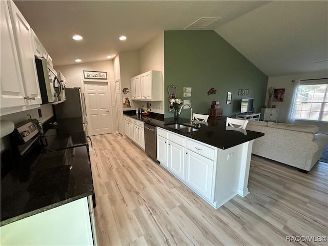 kitchen with stainless steel appliances, dark countertops, open floor plan, and white cabinetry